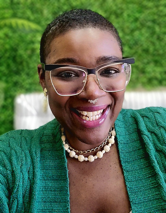 a smiling black woman wearing glasses and a green cardigan